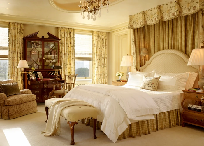 Elegant bedroom with floral curtains, a four-poster bed, and a classic wooden desk and cabinet.