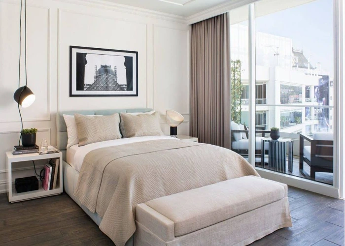 Luxury Dubai bedroom with natural light, large sliding glass doors, and neutral-colored curtains.