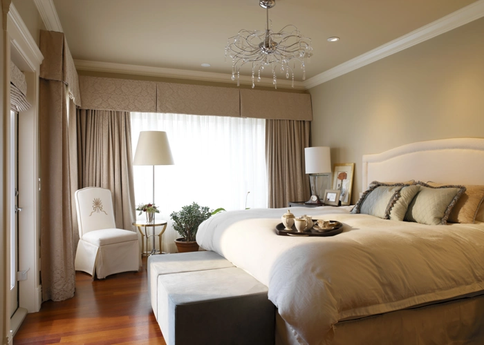 Modern luxury bedroom with neutral tones, a large window with elegant curtains and a chandelier.