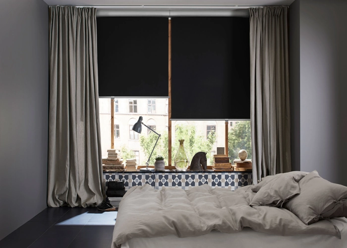 bedroom features a large window with both blackout roller blinds and light-colored curtains.