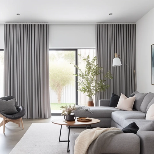 living room with light gray pinch pleat curtains hanging on a track system.