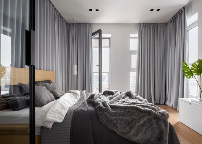 modern bedroom features floor-to-ceiling windows with light gray blackout curtains drawn to the sides.