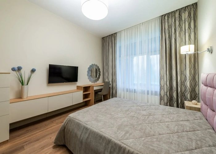 modern bedroom with a large window, featuring light-colored sheer and patterned brown curtains.