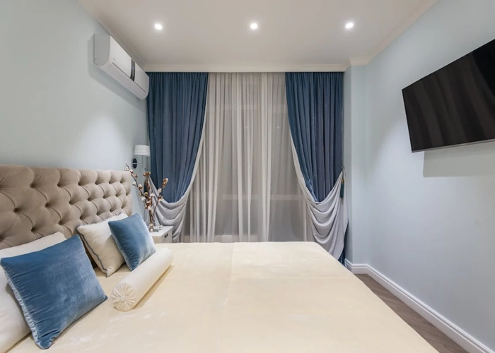 stylish bedroom in Dubai with blue and white curtains and a comfortable bed.