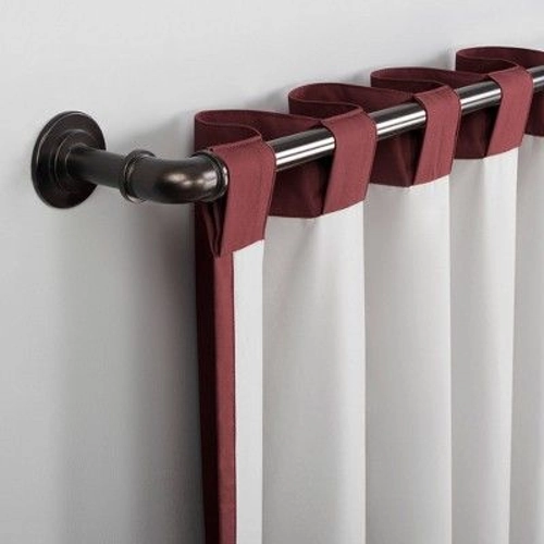 white curtain with a burgundy back tab heading, hanging on a dark bronze curtain rod.